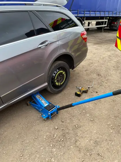 Car on a jack with a space-saver spare wheel being replaced